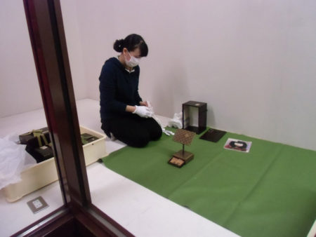 「島津家伝来人形とひな道具展」の展示準備。　慎重に丁寧に作業。
